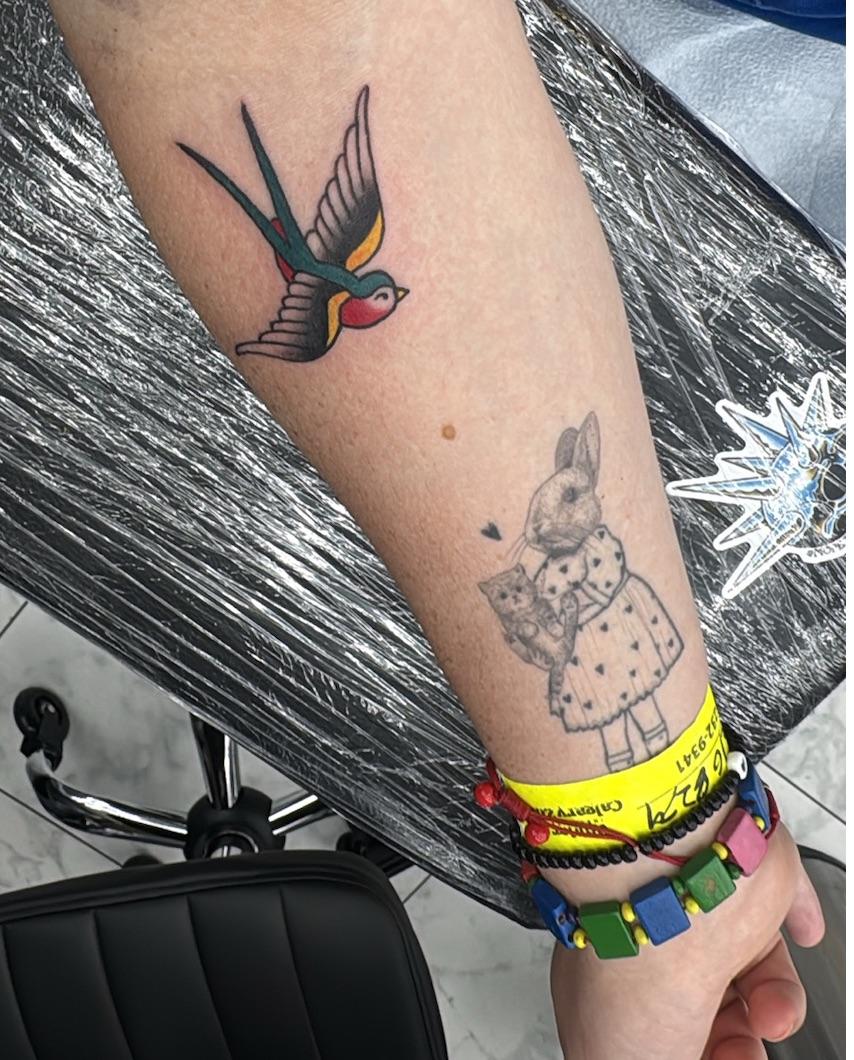 tattoo of little bird, american traditional, on my arm. it's red and yellow and teal. nice birdy