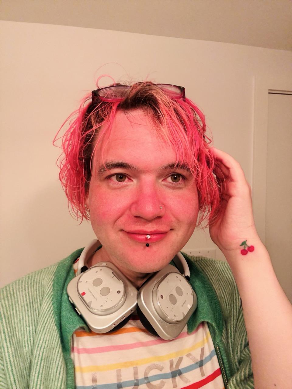 chee rabbits looks into the mirror wearing striped "LUCKY" tshirt and green cardigan. hair pink, face pink, cherry tattoo on the wrist.