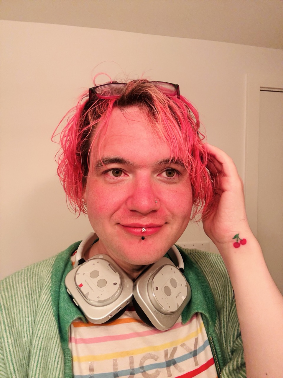 chee rabbits looks into the mirror wearing striped "LUCKY" tshirt and green cardigan. hair pink, face pink, cherry tattoo on the wrist.