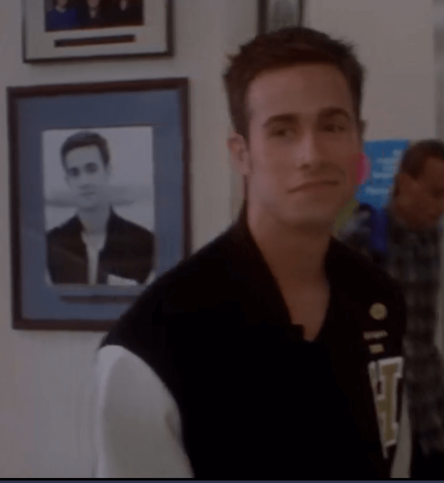 screengrab of freddie prinze jr. in She's All That smiling beside a framed photograph of himself smiling