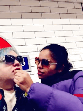 chee having lipstick applied by zaina on the underground. we're wearing
matching sunglasses. mine are blue and hers are
brown.